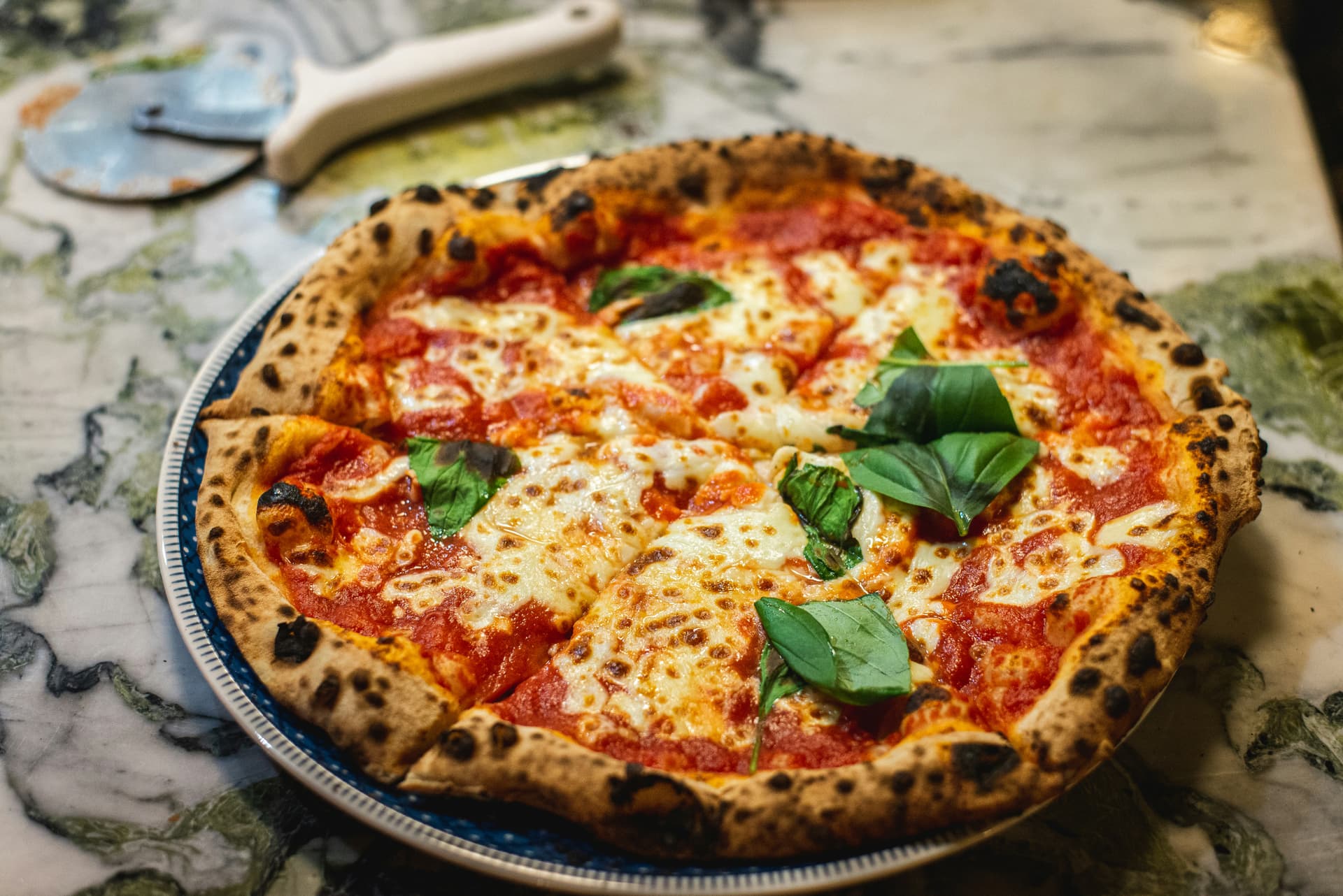 Wood-fired margherita pizza leaving the oven